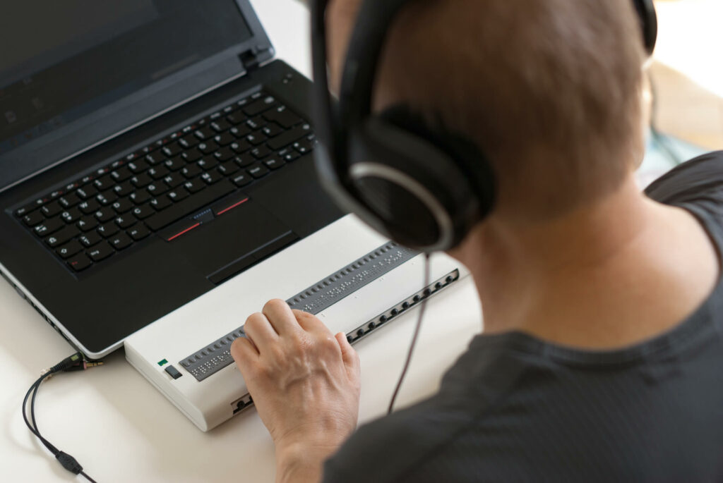 A visually impaired person using a braille keyboard.